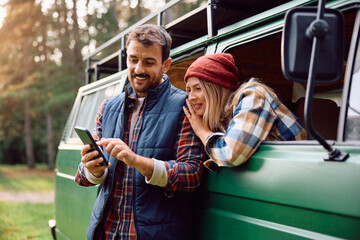 Happy couple using cell phone at camper trailer park.