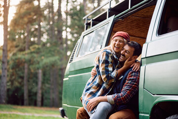 Cheerful couple of campers have fun in their van at trailer park.