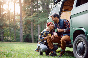 Happy couple enjoys in cup of warm tea while camping in nature in autumn. - obrazy, fototapety, plakaty