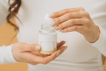 A woman is holding a bottle with pills or vitamins. Mockup, close-up.