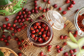 Hawthorn berries macerating in red wine in a glass jar, top view