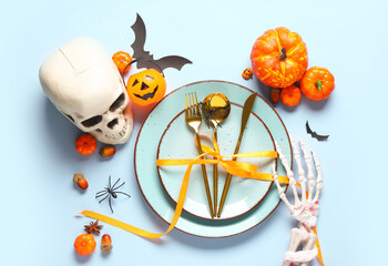 Table setting with pumpkins and Halloween decor on blue background