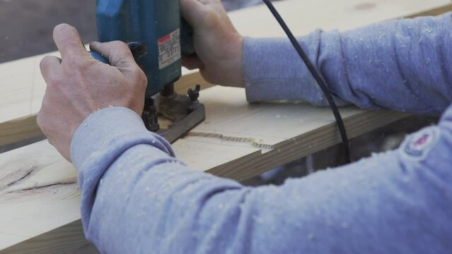 A man processes a board using a router. Carpentry work. Hands close-up