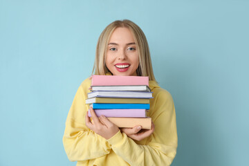 Beautiful young happy woman with many books on blue background
