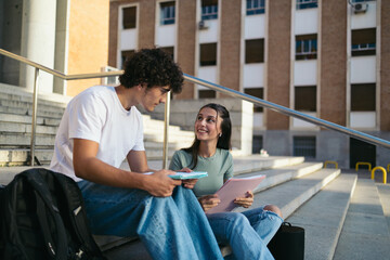 Obraz premium Young college students with casual clothes sitting on stairs outdoors at university and talking while talking and studying 