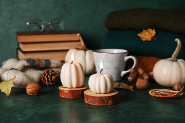 Beautiful autumn composition with candles, pumpkins and cup of tea on dark green background
