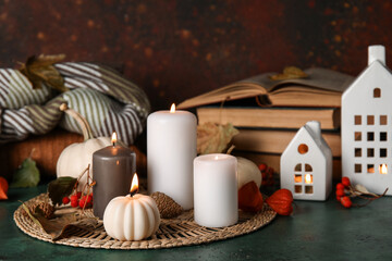 Beautiful composition with candles, books and autumn decorations on dark green background