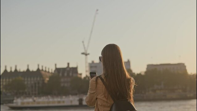 Back view of young tourist woman talking a photo of Big Ben Palace of Westminster on a beautiful sunny day in London UK