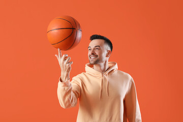 Happy young man with ball on orange background