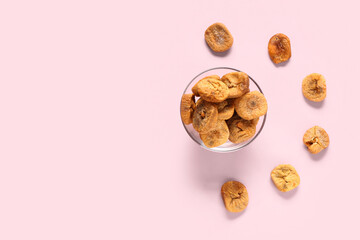 Glass bowl with sweet dried figs on pink background