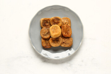 Plate with sweet dried figs on white background