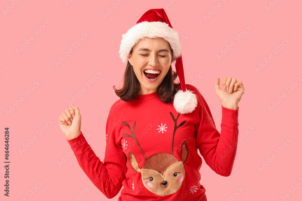 Poster beautiful happy young woman in pajamas and santa hat on pink background