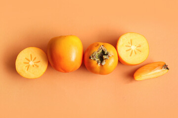 Sweet ripe persimmons on orange background