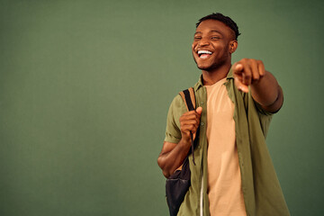 Educational concept. Joyful black man in casual clothes holding backpack on one shoulder and...