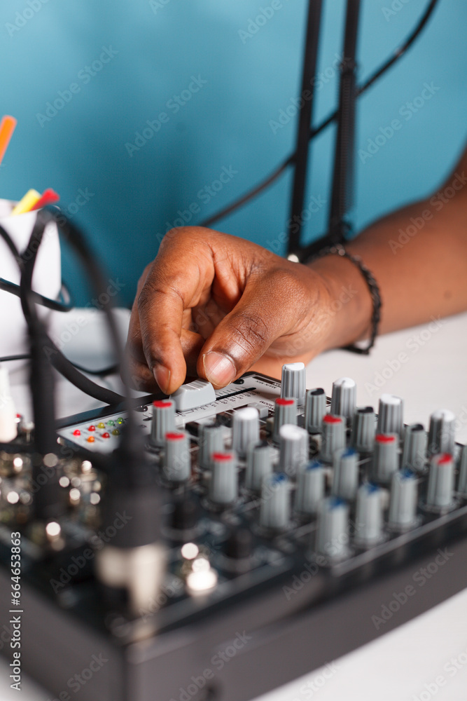 Poster man arm turning knob cap on volume controller in blogger studio close up. african american vlogger u