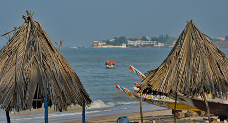 West Africa. Senegal. Conical umbrellas made of reeds and long palm leaves on the sandy beach of the resort town of Ngaparou on the Atlantic Ocean. © Александр Катаржин