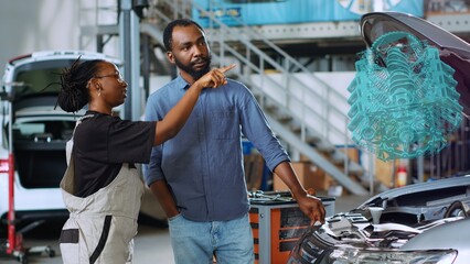 Mechanic in car service using holographic augmented reality to show woman defective components inside automobile. Experienced garage worker using advanced AR software to project vehicle engine