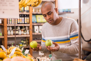 Buyer carefully selects ripe apples in a grocery supermarket