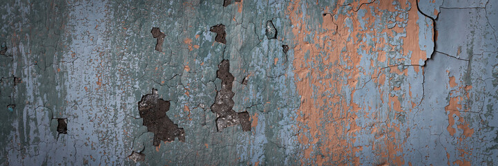 Peeling paint on the wall. Panorama of a concrete wall with old cracked flaking paint. Weathered rough painted surface with patterns of cracks and peeling. Grunge texture for wide panoramic background