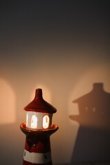 burning candle in a candlestick in the shape of a lighthouse with a shadow, cozy warm atmosphere