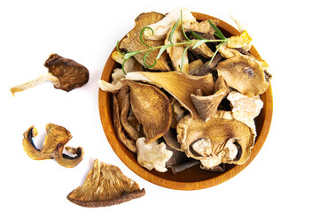Dry slices of different mushrooms in a wooden bowl as gourmet food ingredient, white background top view, Vegetable organic protein trend food.