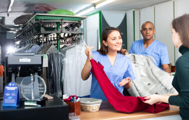 Laundry workers giving clean clothes to client