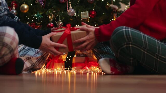family couple exchange gifts box sitting under decorated Christmas tree baubles balls and blinking golden lights garland. tradition boxing day next morning after Christmas night concept - Powered by Adobe