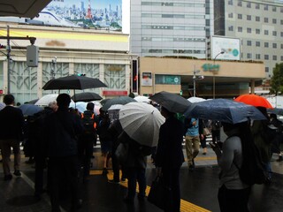 雨の降る駅前で信号を待つ群衆