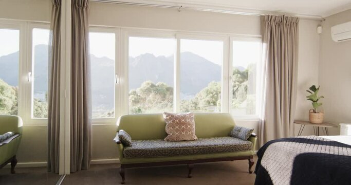 Panning shot of sunny bedroom home interior with views to mountainside, slow motion