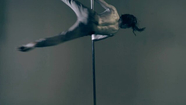 Sexy body of young man. Pole dancer. Sexy man exercise pole dance. Fit slim sexy man performs sensual pole dance. Go-go dancer. Strip dancer. Male athlete doing acrobatic trick on pylon.