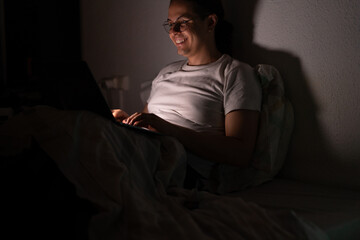 Fototapeta premium young man watching a series in bed at night after a long day at work