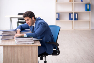 Young male employee and too much work in the office