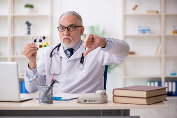 Old male doctor holding molecular model
