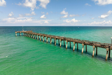 Fototapeta premium Idyllic summer day over Venice fishing pier in Florida. Summer seascape with surf waves crashing on sea shore