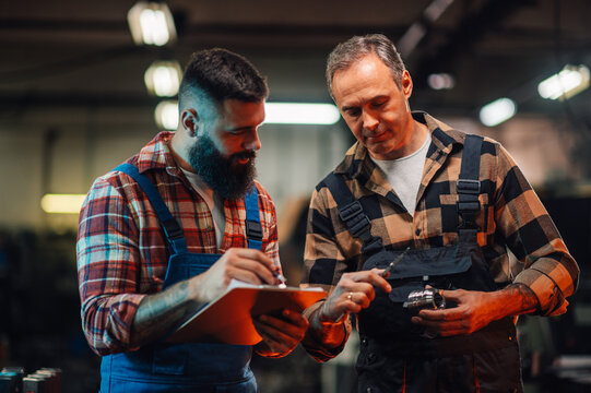 A metallurgy engineer and his assistant taking measures of a metal part.