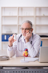 Old male doctor cardiologist working in the clinic