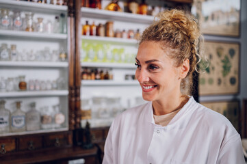 Fototapeta premium Portrait of a cheerful pharmacist standing in a vintage pharmacy and smiling.