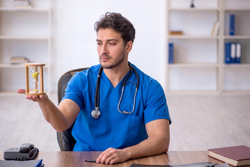 Young male doctor in time management concept