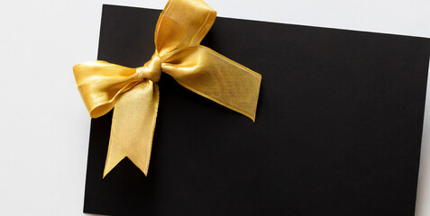 blank black gift card or gift voucher with gold ribbon bow isolated on white background with