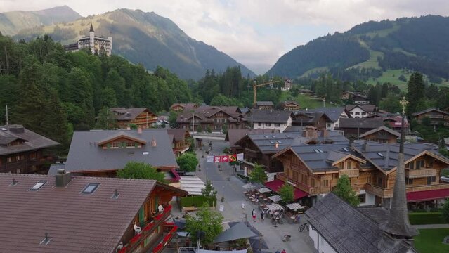 Aerial view of luxurious tourist destination in alpine valley. Beautiful houses and chalets in small town surrounded by mountains. Gstaad, Switzerland