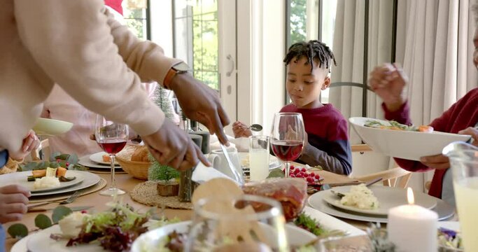 African american father carving meat at multi generation family christmas dinner table
