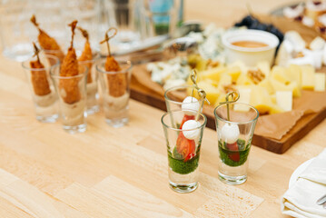 Fototapeta na wymiar catering, food and drinks concept - close up of different appetizers in glasses on table