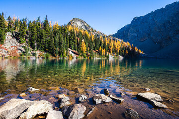 Picturesque view on Blue Lake. Autumn mountains landscape with Blue Lake and bright orange larches...