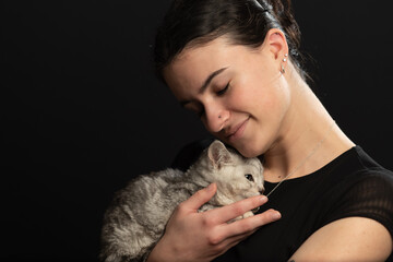 Egyptian Mao kitten snuggles against young lady as they enjoys each others warmth