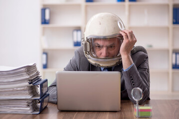 Old male employee wearing spacesuit in the office