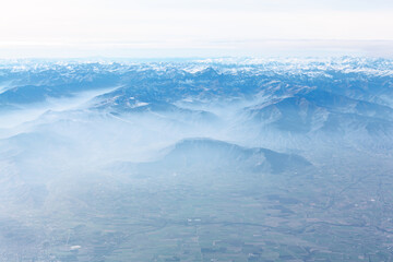 Aerial view of clouds in the blue sky above the mountain range . Fog over the snowy peaks