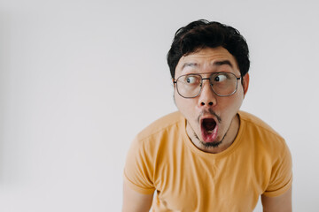 Funny asian man wow and shocked face wear yellow t-shirt isolated o n white. - obrazy, fototapety, plakaty