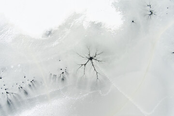 Aerial top-down winter view of frozen lake surface, ice texture with cracks, underwater streams...