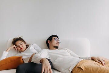 Bored and depressed mood asian lover couple lie on sofa in free empty day.