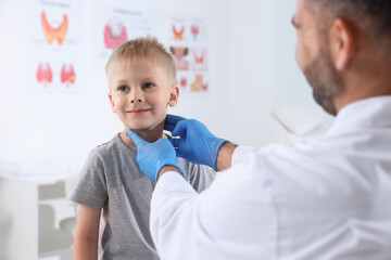 Endocrinologist examining boy's thyroid gland at hospital